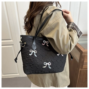 Detail of black quilted tote bag with colorful embroidered bows worn on the shoulder