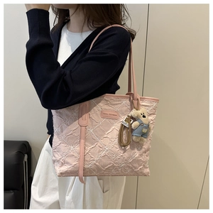Dettaglio borsa tote rosa trapuntata con ricami floreali e ciondolo a forma di orso