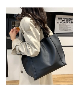 Vista posteriore di una borsa tote nera in ecopelle indossata da una modella in un interno