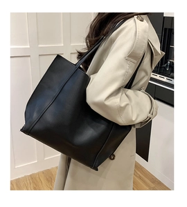Grande borsa tote nera opaca in finta pelle indossata con un trench beige elegante