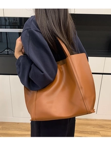 Dettaglio di una grande borsa tote in pelle marrone con manici lunghi sulla spalla