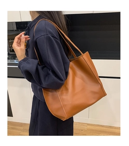 Brown vintage leather tote bag shown on shoulder with minimalist stitching detail