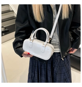 Close-up of white glossy pillow bag showing shiny patent leather finish and gold hardware