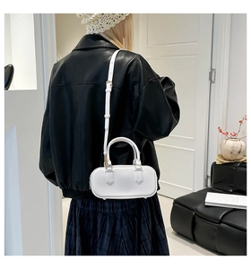 White pillow bag with adjustable strap shown on a model in a minimalist setting