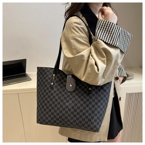 Detail view of the large monogram tote bag with chic leather straps and metal rivets
