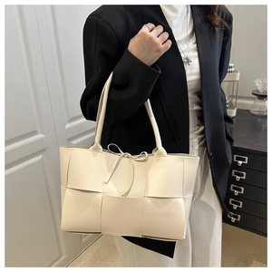 Detail of beige wide-grid woven tote bag with matte leather texture and tie detail