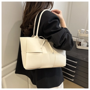 Detail of an ivory woven leather tote bag shown on model with wide strap texture
