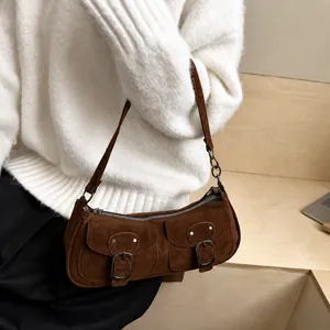 Brown suede baguette bag with vintage buckles worn over a white knit sweater