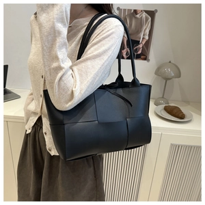 Gros plan détaillé d'un sac cabas en cuir tressé noir avec un design de tissage large