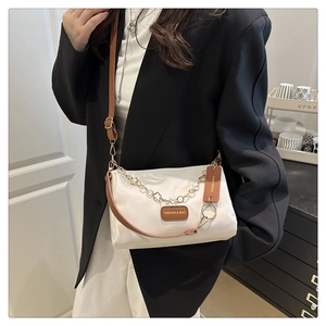 Détail du sac polochon crème avec chaîne cœur dorée et garniture en cuir marron