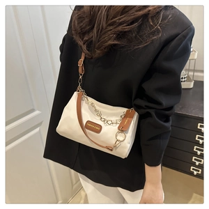 Vue détaillée du sac en tissu blanc avec garniture en cuir marron et chaîne dorée