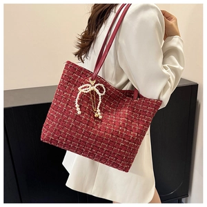Detail der roten Tweed-Tasche mit Perlen-Schleifen-Anhänger und Lederriemen