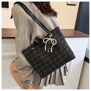 Detailansicht der schwarz-goldenen Tweed-Tasche mit Perlenbogen an einem Model