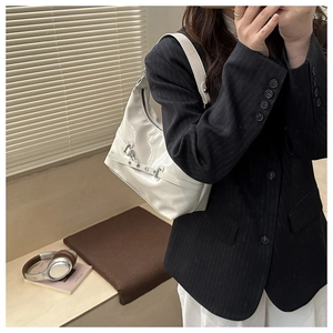 Detail of white patent leather crescent shoulder bag with metallic buckle and strap decor