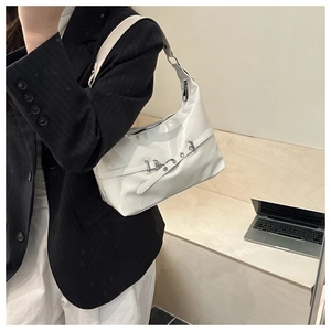 Détail du sac à bandoulière en cuir verni blanc avec boucle mors en métal argenté élégante