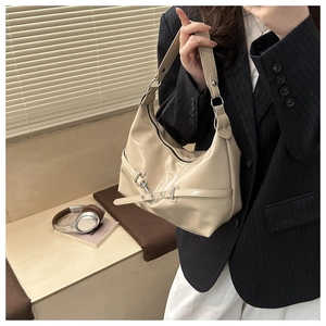 Close-up of beige patent leather handbag with silver chain detail on model
