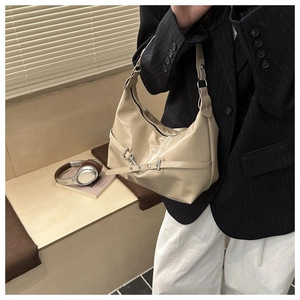 Détail d'un sac hobo demi-lune blanc crème avec sangle décorative et boucles argentées