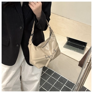 Détail d'un sac hobo beige avec une boucle en métal argenté et une bandoulière