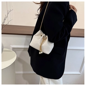 Texture dettagliata della borsa a secchiello in velluto bianco con catena d'oro e perle