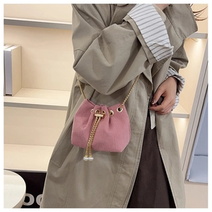 Dettaglio borsa a secchiello in velluto rosa con catena dorata e perle sul cordoncino