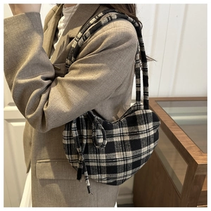 Détail d'un sac à bandoulière en laine à carreaux noir et blanc porté avec un blazer marron