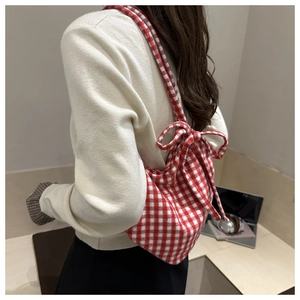 Détail du sac fourre-tout en toile à carreaux rouge et blanc avec bretelles à nœud