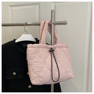 Close-up of pink quilted puffer tote bag featuring heart pattern and drawstring detail