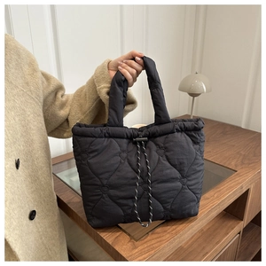 Detail of heart-quilted black tote bag showing white textured drawstring and soft nylon fabric