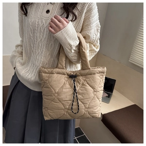 Detail view of heart-shaped quilted pattern and drawstring closure on beige tote bag