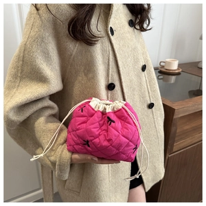 Macro shot of rose red quilted drawstring cosmetic bag with black bow and fabric texture