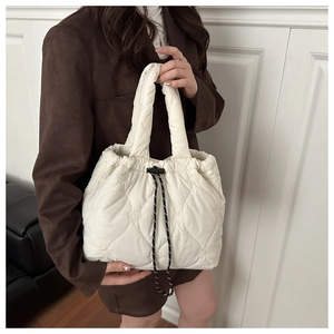 Detail of off-white heart quilted tote bag with woven drawstring and textured finish