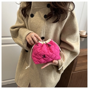 Close-up of quilted drawstring cosmetic bag in rose pink with black bow embroidery details