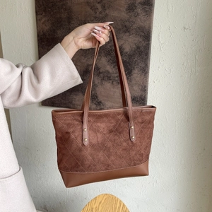 Détails du sac fourre-tout en daim marron avec surpiqûres et rivets dorés polis