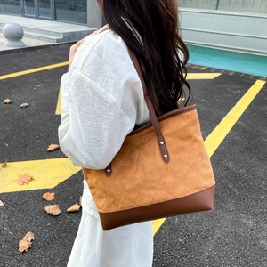Détail du sac cabas matelassé bicolore en daim marron et cuir avec finitions dorées
