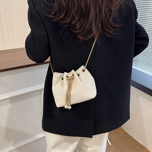 Secchiello chic in velluto a coste beige con catena dorata e perle su blazer nero