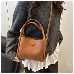 Brown faux leather bucket bag shown as a crossbody and handbag on a model's outfit