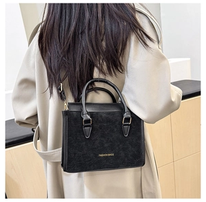 Détail du sac à main en cuir noir avec texte doré et bandoulière réglable amovible