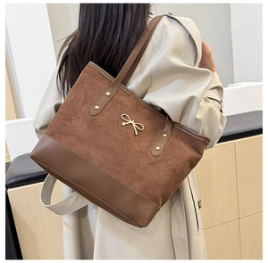 Détail du sac cabas marron foncé avec boucle nœud doré et textures élégantes de matériaux