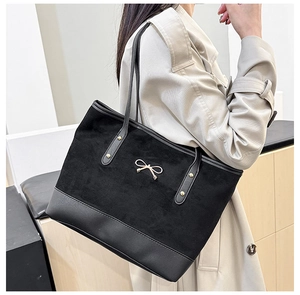 Détail du sac cabas noir avec textures en daim mélangées et nœud doré élégant