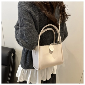 Close-up of cream white bucket bag with matte faux leather and refined metal hardware