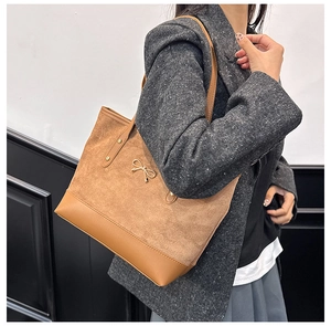 Détail du sac cabas en daim avec boucle nœud dorée et design patchwork en cuir lisse