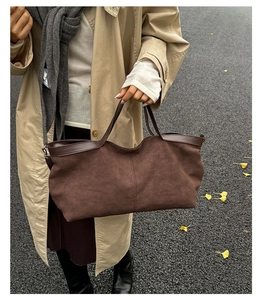 Detail view of brown faux suede tote bag with contrast leather trim on autumn street