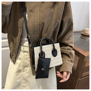 Detail of woven straw mini bag with black faux leather handles and detachable long strap