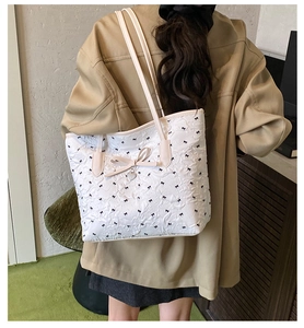 Détail du sac cabas matelassé blanc avec mini nœuds noirs et pendentif en cœur