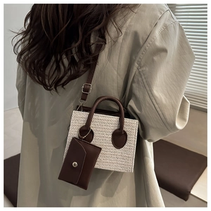 Détail du sac à main en paille tressée avec bordure en cuir marron et mini pochette assortie