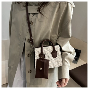 Detalle de mini bolso de paja trenzada con asas de cuero marrón y bolsa desmontable