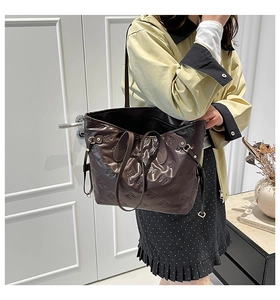 Detailed macro view of chocolate brown tote bag with embossed bow textures and PU leather