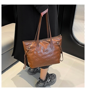 Close-up of brown glossy tote bag with embossed rabbit pattern and drawstring side detail