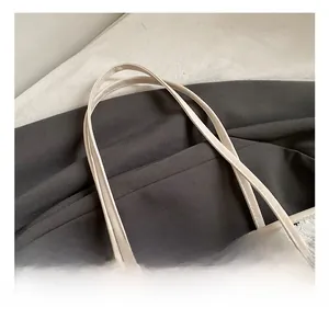 Détail de la poignée en cuir beige et du motif nœud sur un sac cabas plissé blanc