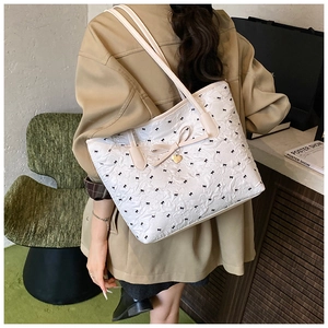 Gros plan du sac cabas matelassé blanc avec motifs nœuds et pendentif cœur doré
